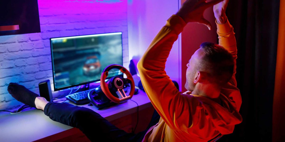 male-gamer-playing-racing-games-computer-he-uses-steering-wheel-emotional-game